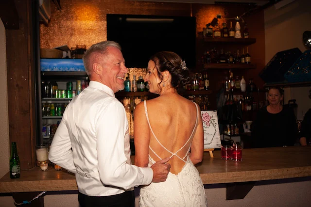 A newlywed couple smiling together at the reception bar