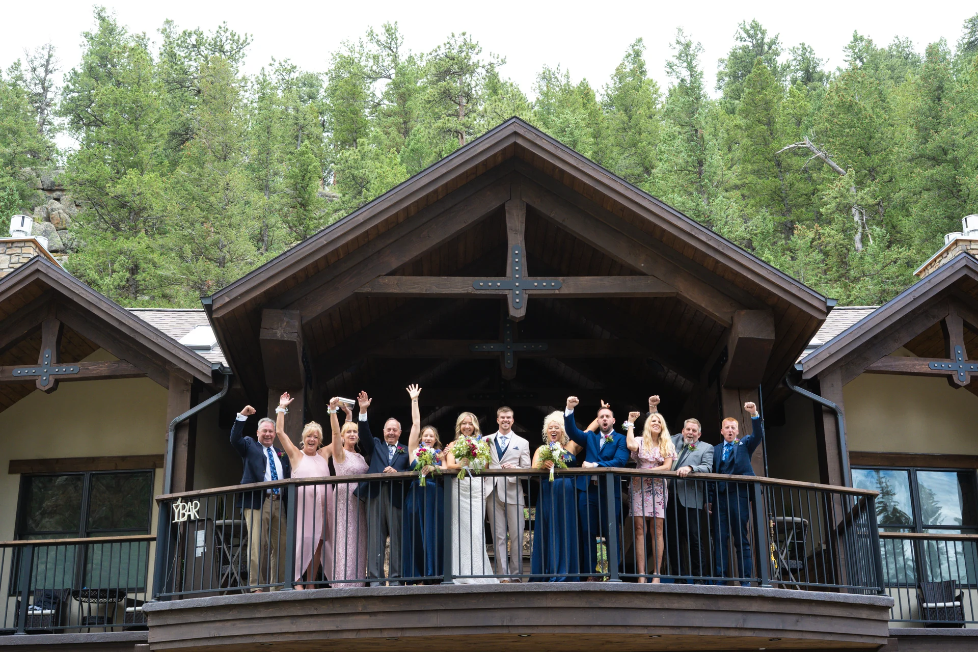 A wedding party celebrating together on a balcony beneath a timber-framed roof